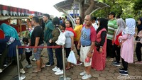Pengunjung mengantre menaiki kereta wisata untuk keliling Monas.