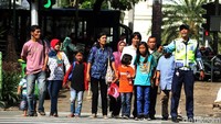 Petugas Dishub tampak sibuk menyebrangkan warga dan para pengunjung yang akan menikmati Monas di liburan akhir tahun ini.