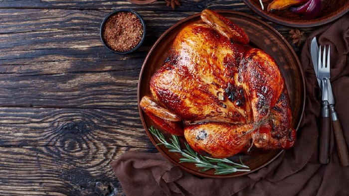 whole roasted chicken with golden brown crispy skin served on a earthenware dish with caramelized grilled pumpkin slices and grilled onion, view from above, flat lay, copy space