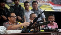 Terlihat sejumlah barang bukti dipajang di meja panjang. Terlihat ada 4 senjata laras panjang, 6 pucuk senjata laras pendek.
