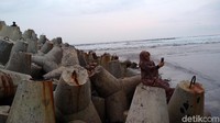 Gaya salah satu wisatawan berfoto dengan batu pemecah ombak. (Faizal Amiruddin/detikcom)