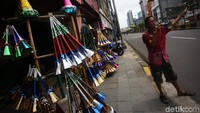 Seorang pedagang meniup terompet yang dijualnya untuk menarik minat pembeli.