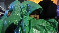 Sebagian warga juga mengenakan jas hujan dan payung untuk mengantisipasi hujan yang lebih deras.