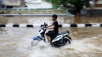 Pengendara menggeber motornya agar tidak mogok di tengah banjir.