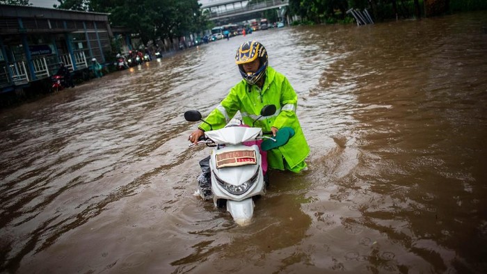 BANJIR DI CAWANG Warga mendorong motornya di dekat taksi yang terendam genangan banjir di Jalan DI Panjaitan, Cawang, Rabu (1/1/2020). Banjir tersebut disebabkan karena tingginya intensitas hujan yang mengguyur sejak Selasa (31/12/2019). ANTARA FOTO/Aprillio Akbar/foc.