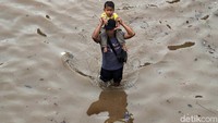 Seorang anak harus dipanggul orangtuanya saat menerobos banjir.