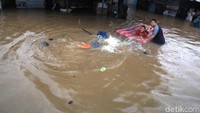Warga tampak asyik bermain banjir meskipun genangan cukup tinggi.