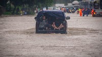 Mobil nekat melintas ditengah genangan banjir yang hampir menutupi hampir separuh badan mobil.