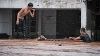 Salah satu petugas damkar bertelanjang dada sementara satu lainnya hanya berkaus. Mereka berenang mengarungi arus deras hingga akhirnya mencapai pagar rumah tempat si anjing terjebak. Rantai dilepaskan lalu tali dipasang di kalung anjing tersebut. (Foto: Gala Indiga)