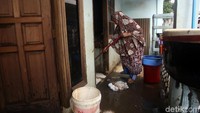 Warga membersihkan rumahnya dari lumpur sisa banjir yang sebelumnya merendam kawasan Cipinang Melayu.