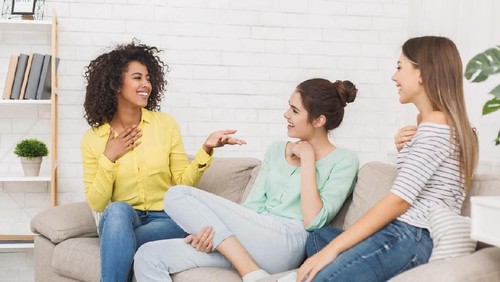 Two female friends talking on a bench in autumn park