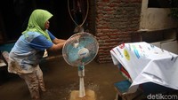 Seorang warga barang elektronik di rumahnya yang kotor akibat terendam banjir.