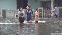 Seorang bapak menggendong anaknya menerobos banjir.