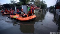 Dengan perahu karet mereka meyelusuri jalan-jalan yang berubah jadi sungai.
