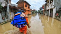 Petugas menggendong seorang ibu menerobos banjir.