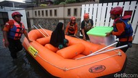 Sementara ibu ini memilih naik perahu karet menuju pengungsian.