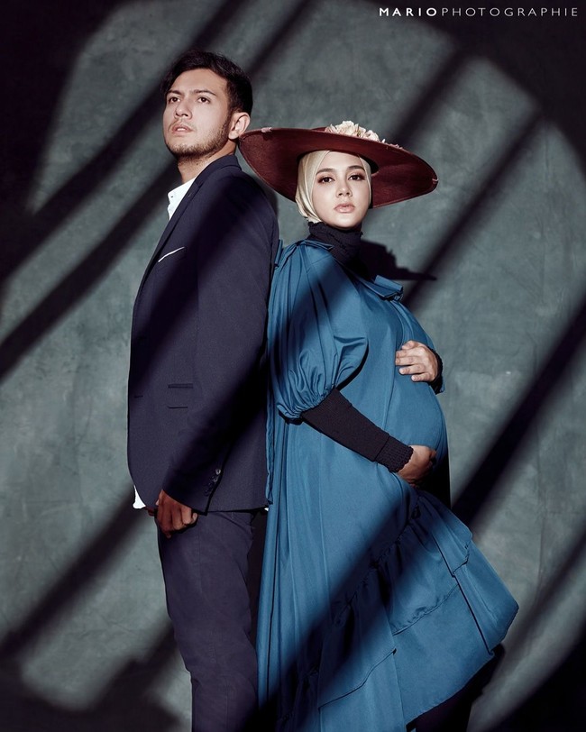 Bernuansa ala wanita bangsawan dengan topi khas bangsawan Inggris, Biby memakai dress warna hijau tosca dengan manset warna hitam dan memakai hijab warna nude dengan tambahan aksesori floppy straw hat. Sementara Rifky menyesuaikan penampilannya dengan memakai setelan jas warna biru dongker. Foto: instagram @mariophotograhie.