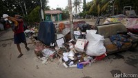 Seorang warga tengah membuang barang yang rusak akibat banjir.