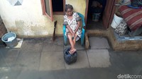 Seorang lansia tengah bersantai di depan rumahnya.