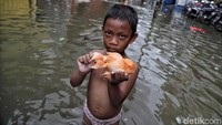 Tak hanya ramai dengan aktivitas para pedagang maupun pembeli, ada pula anak-anak yang asyik bermain air maupun mencari ikan di tengah banjir.