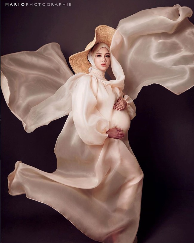 Iwan Latif sebagai stylist membuat Biby tampil memesona dalam balutan dress berwarna nude yang dipadukan dengan hijab bahan organza. Dia juga memakai memakai aksesori Floppy Hats warna cokelat. Foto: instagram @bibyalraen13