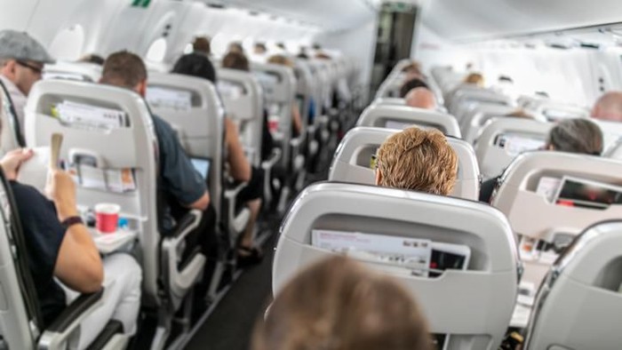 High quality stock photo of a young boy playing and using a tablet computer on an airport plane.
