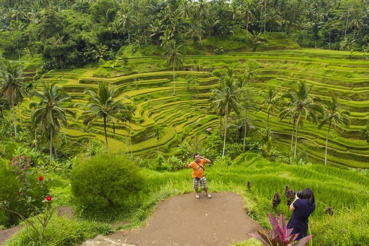 Tegalalang, Bali, Indonesia - April 19, 2013: A tourist has his photograph taken in front of traditional Balinese rice terraces