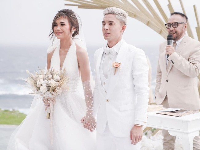 Dekorasi kayu dan serba putih menjadi pilihan Kim Kurniawan dan Elisa untuk pernikahan mereka. Pasangan pemain bola dan selebgram itu pun berpose bahagia bersama keluarga. Tampak kakak Kim, Jennifer Bachdim tersenyum bahagia bersama suaminya Irfan Bachdim dan kedua anak mereka usai adiknya resmi menikah. Foto: dok. Instagram @bridetsory