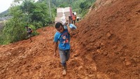Warga korban longsor membawa sejumlah bantuan logistik saat menaiki bukit untuk dapat menuju ke rumahnya yang sulit diakses akibat longsor.