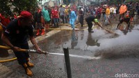 Warga bersama petugas gabungan membersihkan lumpur yang masih tersisa usai banjir melanda wilayah Kecamatan Makassar, Jakarta Timur.