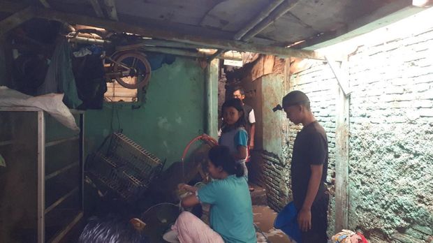 Elin (40) sedang membersihkan barang-barangnya yang terendam banjir.