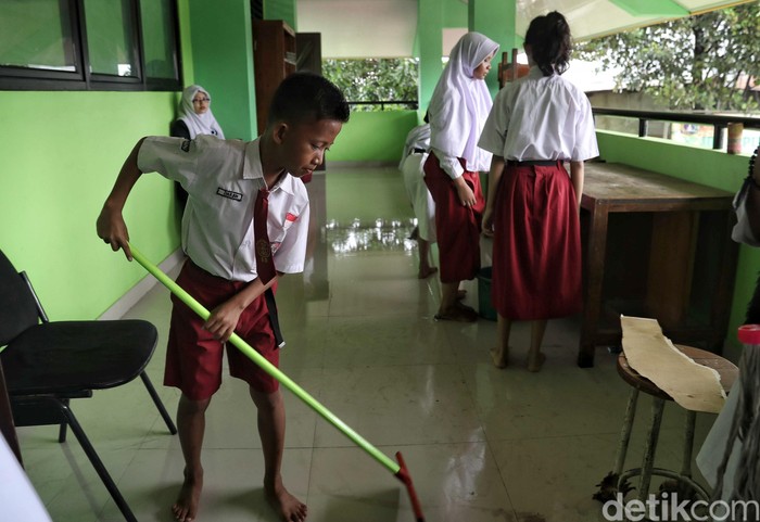 Siswa SDN 01 Kapuk Muara, Jakut, memulai hari pertama masuk sekolah dengan bersih-bersih kelas. Pasalnya sekolah itu sebelumnya terendam banjir.
