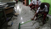 Seorang siswa membersihkan lantai di ruang kelas yang kotor usai terendam banjir di awal tahun 2020.