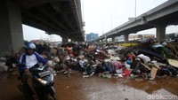 Warga melintas di depan sampah sisa banjir di Cipinang Melayu, Jakarta Timur, Senin (6/1/2020).