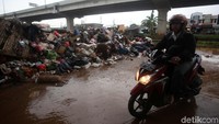 Warga melintas di depan sampah sisa banjir di Cipinang Melayu, Jakarta Timur.