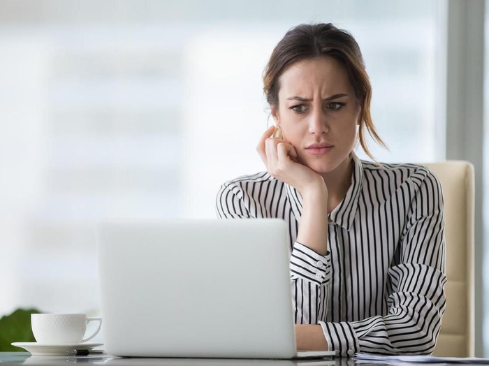 virus corona Shot of a woman using a laptop while blowing her nose with a tissue