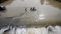Curah hujan yang tinggi menyebabkan air Sungai Cileungsi meluap ke jalan.