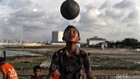 Seorang anak juga tampak asyik bermain sepakbola di kawasan pesisir utara Jakarta yang kerap dilanda banjir rob saat kawasan tersebut masih kering.