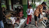 Seorang anak melintas di saat sejumlah guru sedang membersihkan perabotan sekolah.