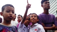 Anak-anak yang baru pulang sekolah ikut penasaran.