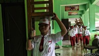 Para siswa dibagi menjadi sejumlah kelompok saat sedang membersihkan sekolah. Ada yang bertugas mengatur bangku dan meja belajar ke ruang kelas, ada pula yang bertugas mengepel dan membersihkan perabotan di dalam ruang kelas.