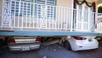 Dua buah mobil nampak terhimpit bangunan yang rusak usai kawasan Puerto Rico diguncang gempa berkekuatan 5,8 pada Senin (6/1) waktu setempat.