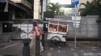 Seorang pejalan kaki melintas diantara gerobak PKL di Jalan Salemba.