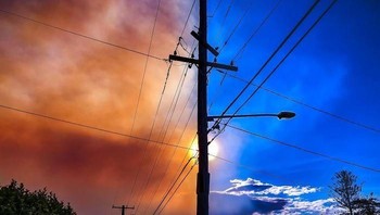 Tiang listrik memisahkan pemandangan langit biru dan langit yang terpapar asap. Foto: Bored Panda