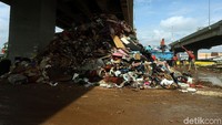 Petugas membersihkan sampah yang menumpuk di kolong tol.