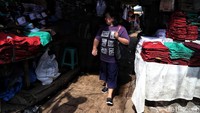 Seorang warga tengah melihat beragam seragam sekolah yang dijajakan para pedagang di Pasar Jatinegara.