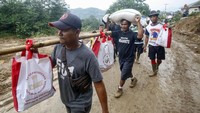 Para relawan harus melewati medan yang licin saat mendistribukan bantuan untuk korban longsor di Desa Harkat Jaya, Sukajaya, Bogor, Jawa Barat.