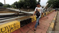 Seorang warga melintas diantara pagar besi yang rusak.