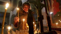 Seorang jemaat menyalakan lilin setelah misa Natal di sebuah gereja di Grozny, Rusia, Senin (6/1) waktu setempat. AP Photo/Musa Sadulayev.