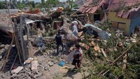 Warga mencari barang-barang yang masih dapat diselamatkan setelah sebuah pohon tumbang menimpa rumah warga di Denpasar, Bali, Rabu (8/1/2020).